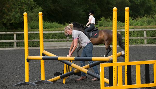 Woman preparing jump for horse riding practice